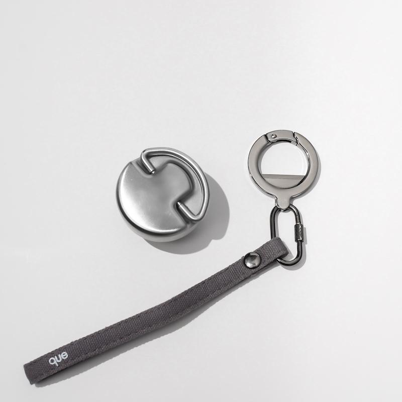 Que Bottle Stainless steel bottle cap with loop and gray wrist strap with keyring and bottle opener.