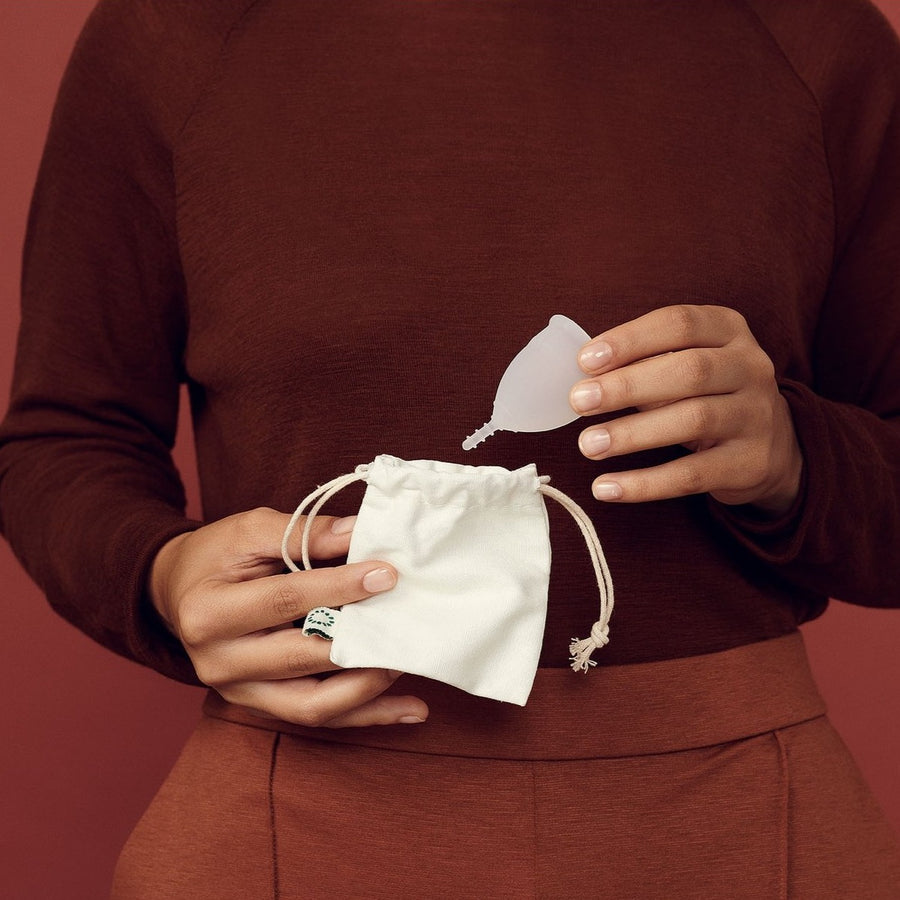 Woman Holding OrganiCup Menstrual Cup And Storage Pouch.
